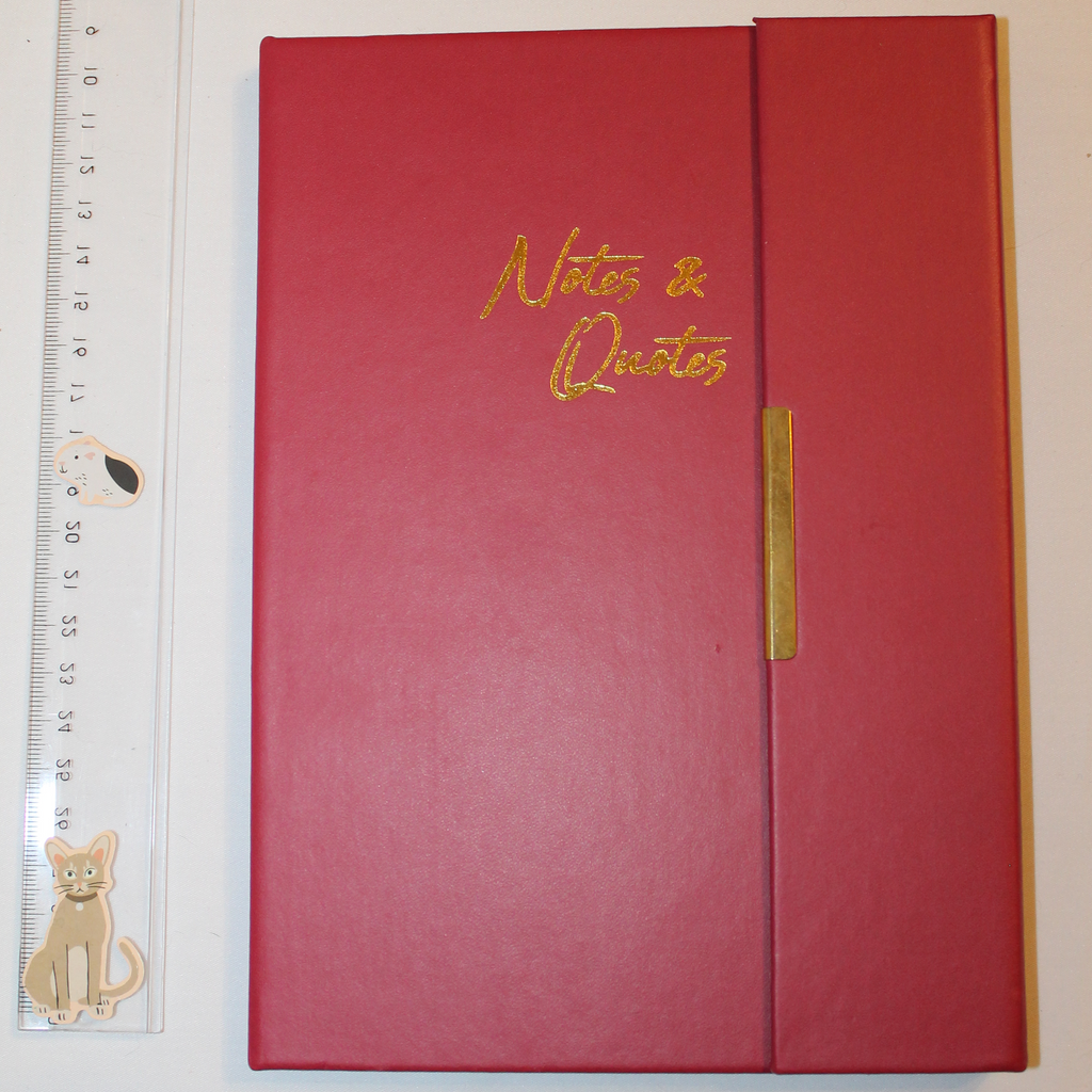 Red notebook with 'Notes & Quotes' on the cover, next to a ruler for scale.