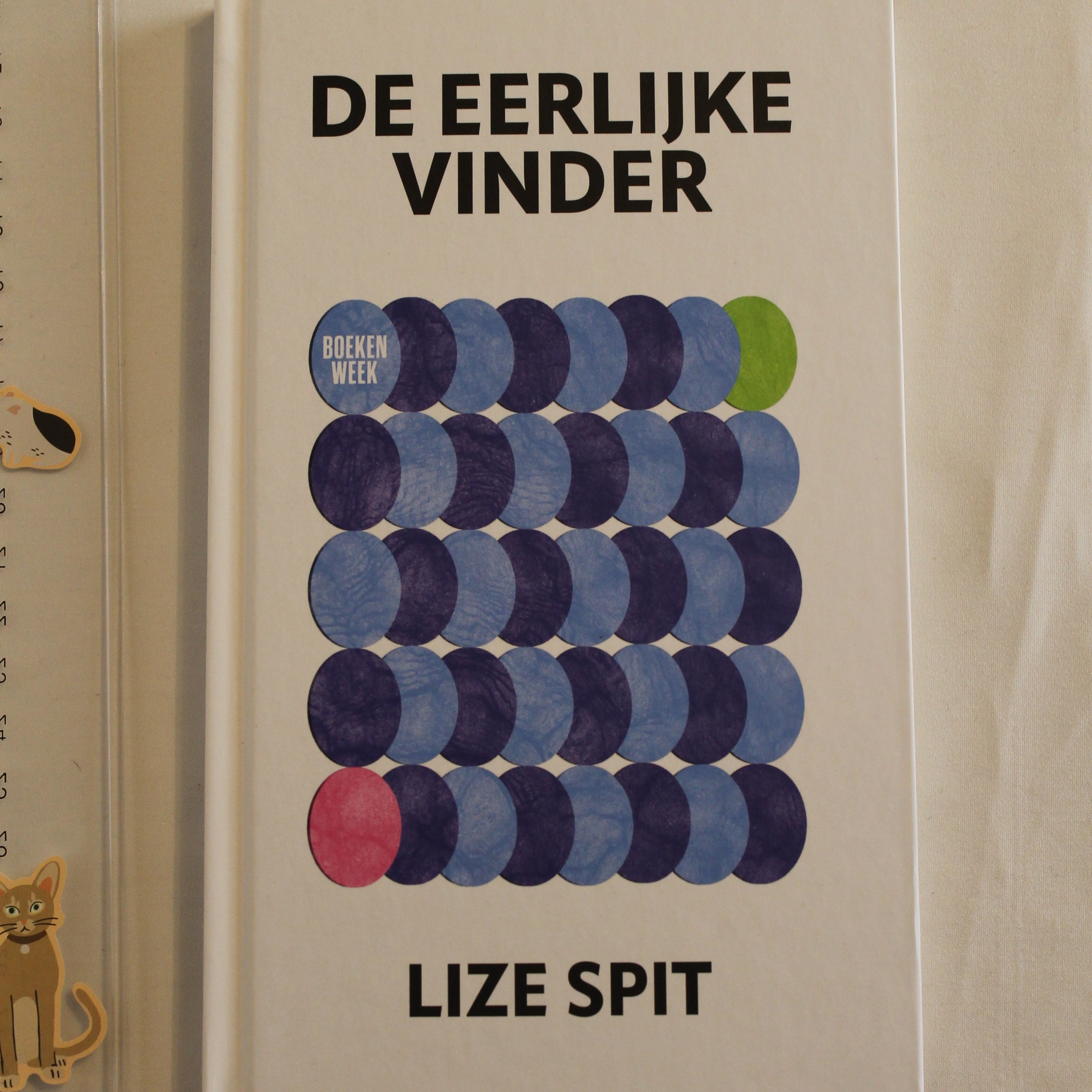 Book titled 'De Eerlijke Vinder' by Lize Spit with colorful circular design on a beige background