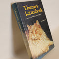 Book titled 'Thieme's Kattenbook' with a cat illustration on the cover, placed on a beige surface.