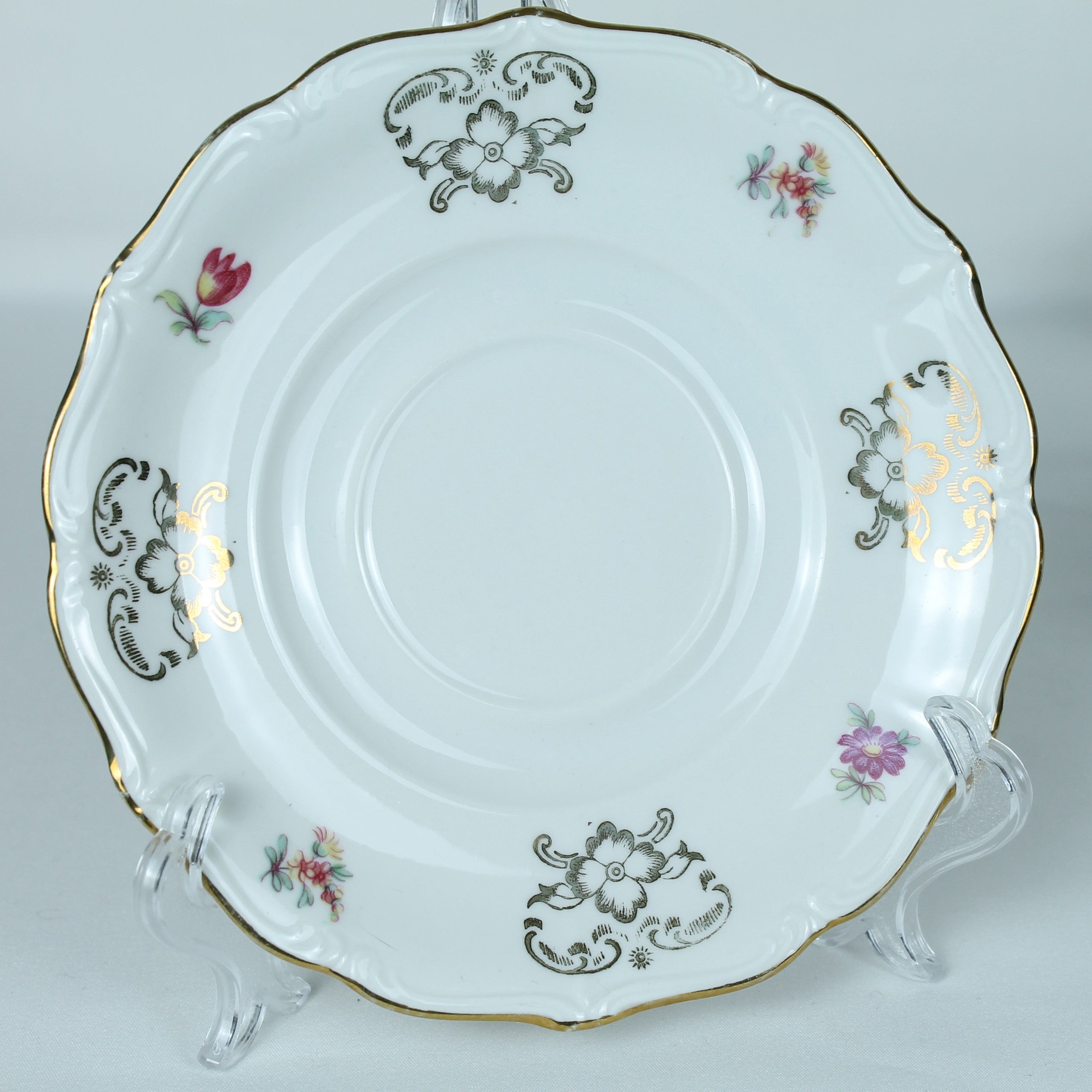 Decorative ceramic plate with floral patterns on a stand against a light background