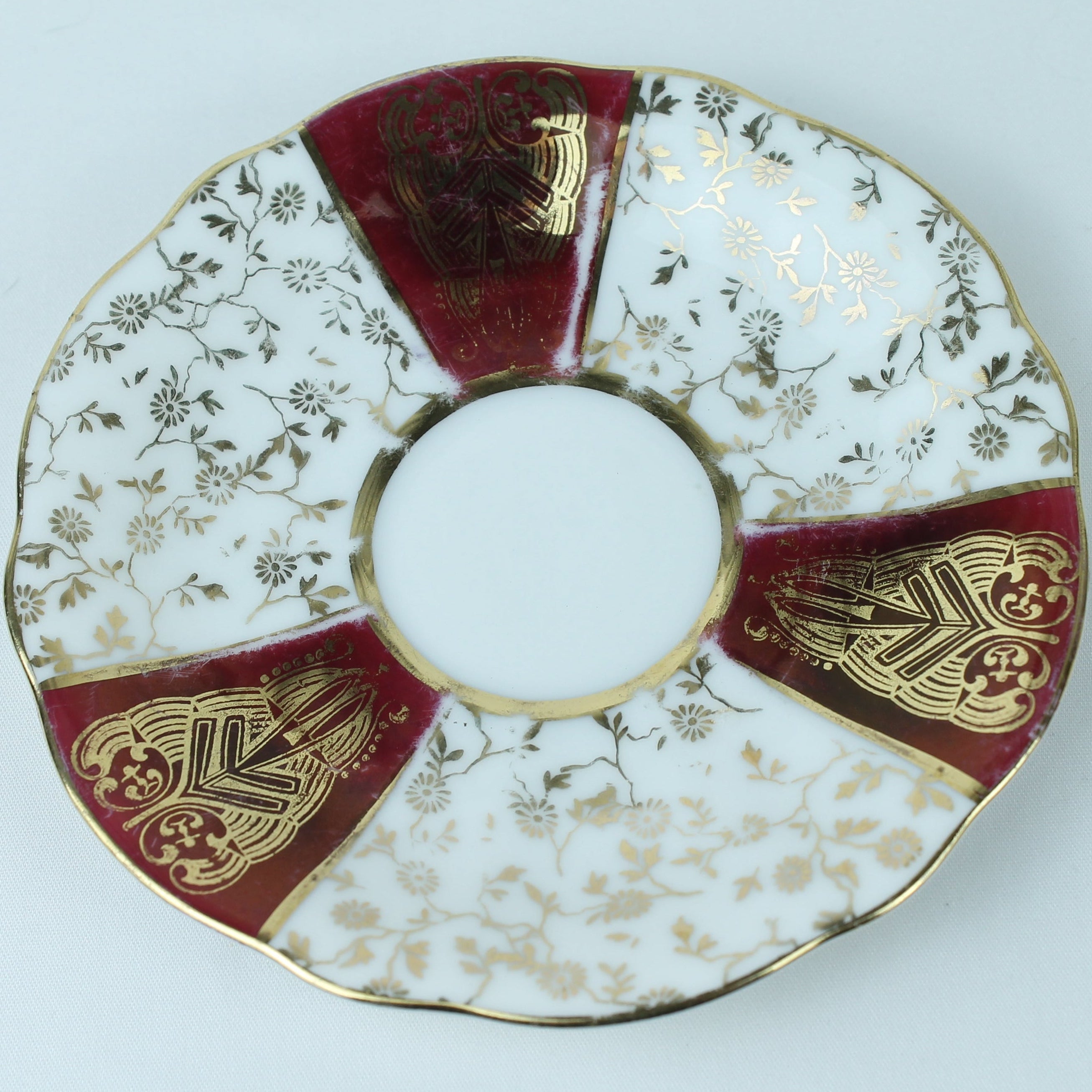 Decorative plate with red, gold, and white patterns on a white background