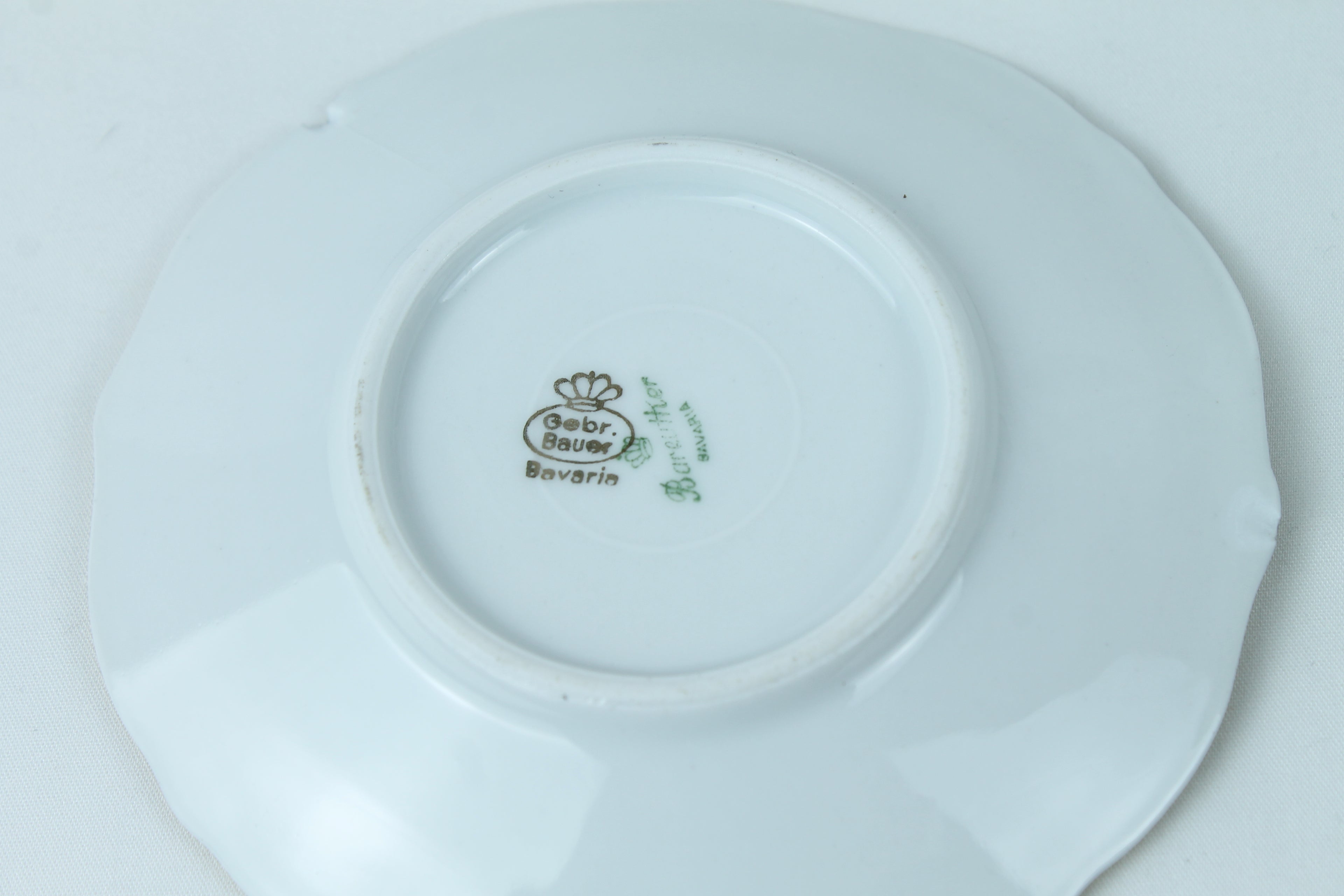 Close-up of a white ceramic plate with a visible brand logo on a light gray background