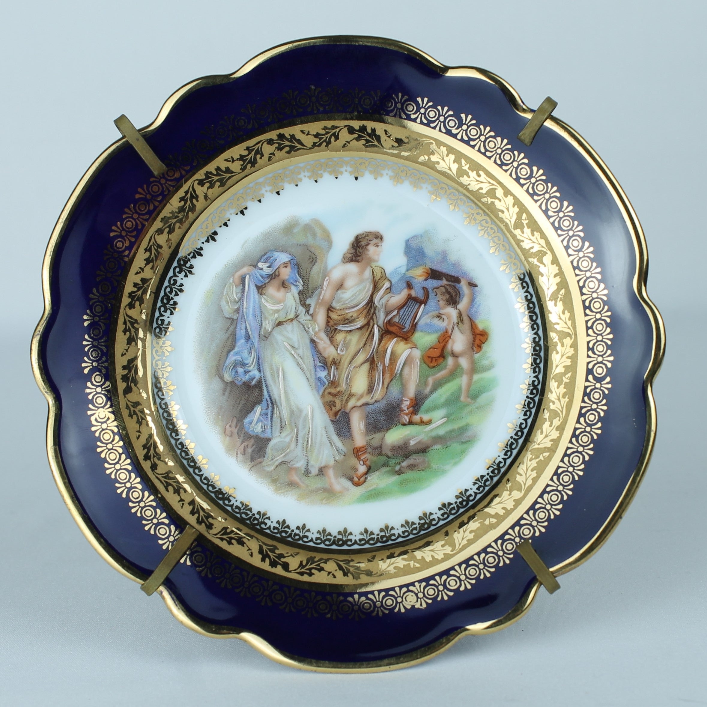 Decorative plate with classical scene and gold embellishments on a light blue background