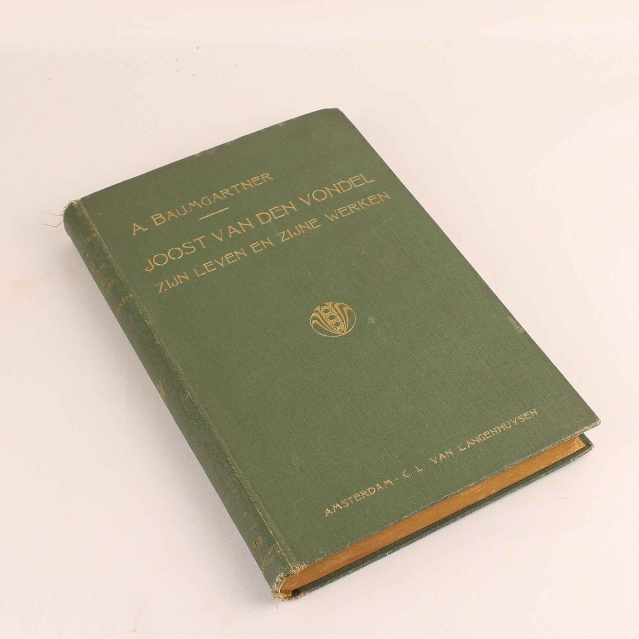 Green book with gold text and a logo on a beige background