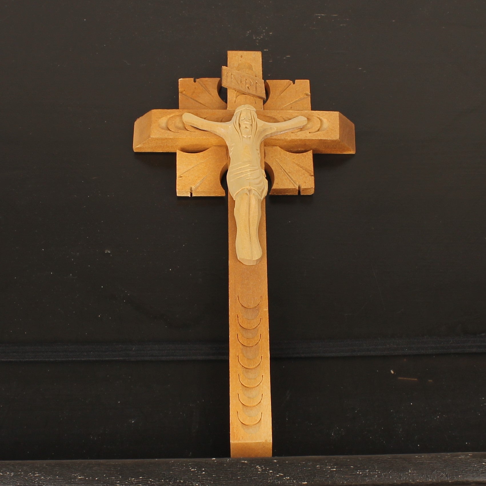 Wooden cross with a figure on it against a black background