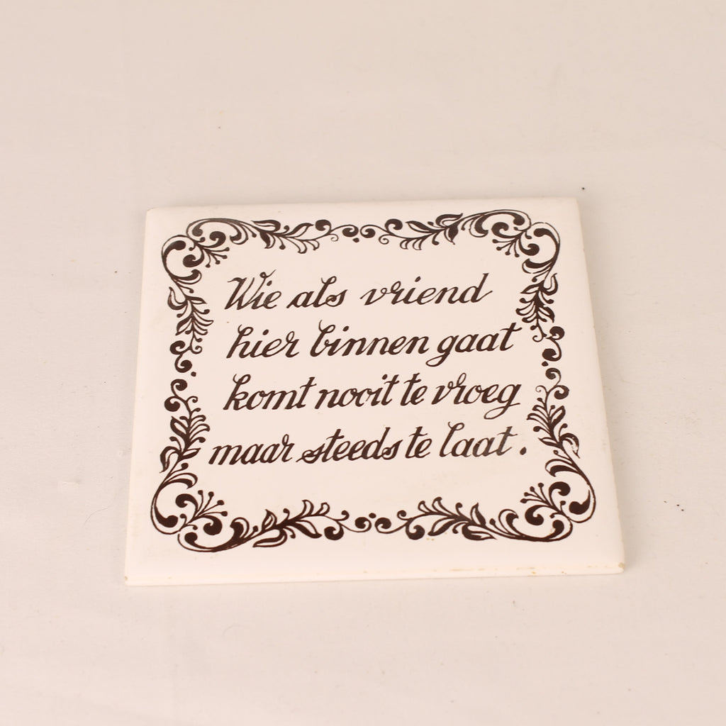 Square ceramic tile with decorative text and border on a beige background