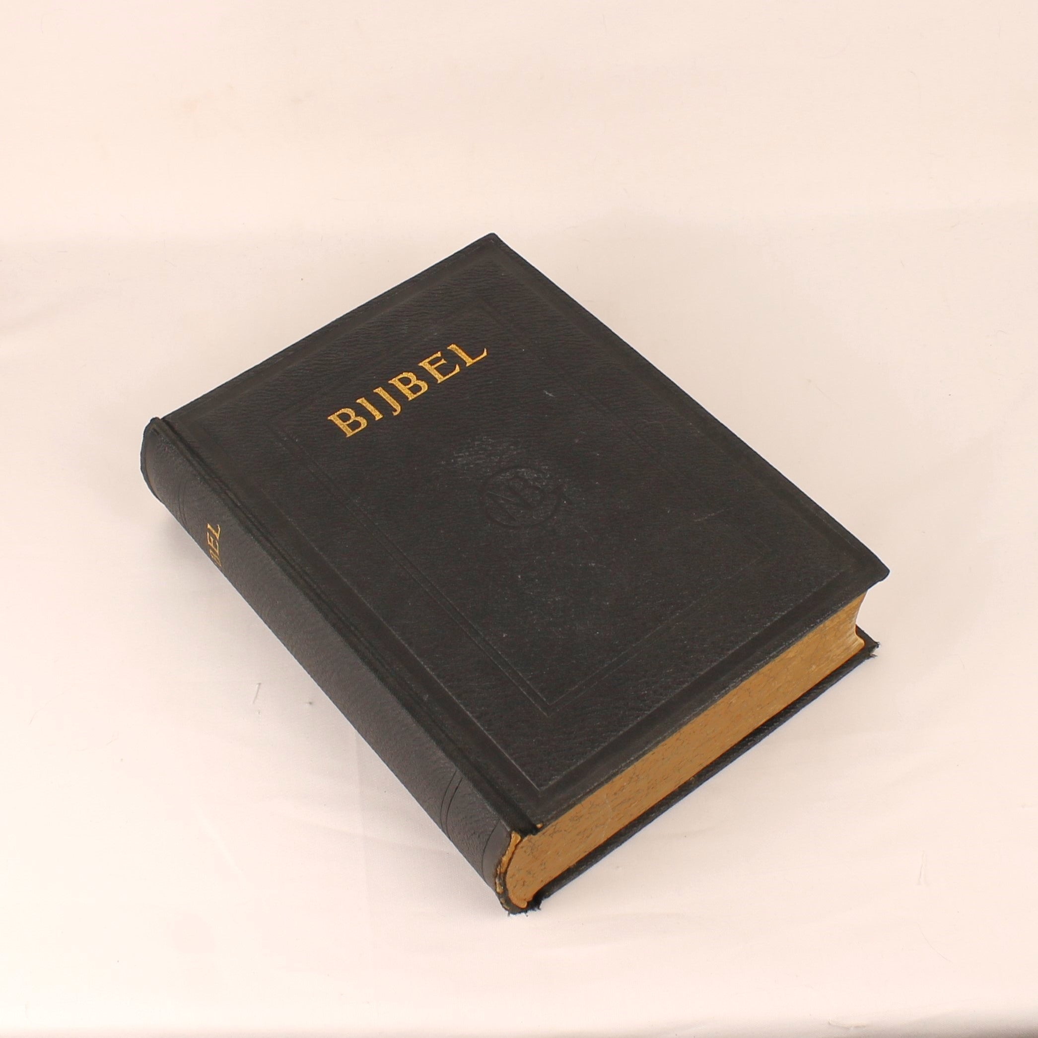 Black Bible with 'BIJBEL' embossed on the cover against a beige background