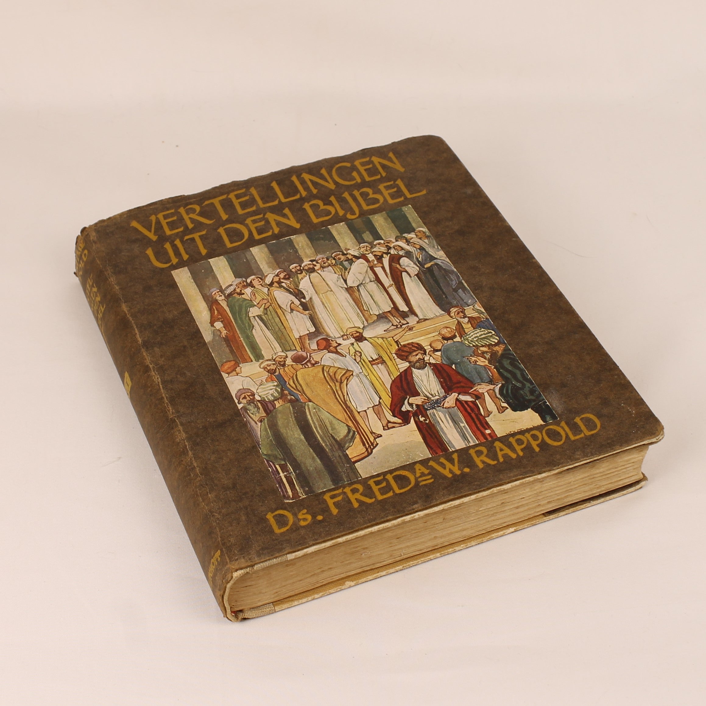 Vintage book titled 'Vertellingen uit den Bijbel' with decorative cover on a beige background