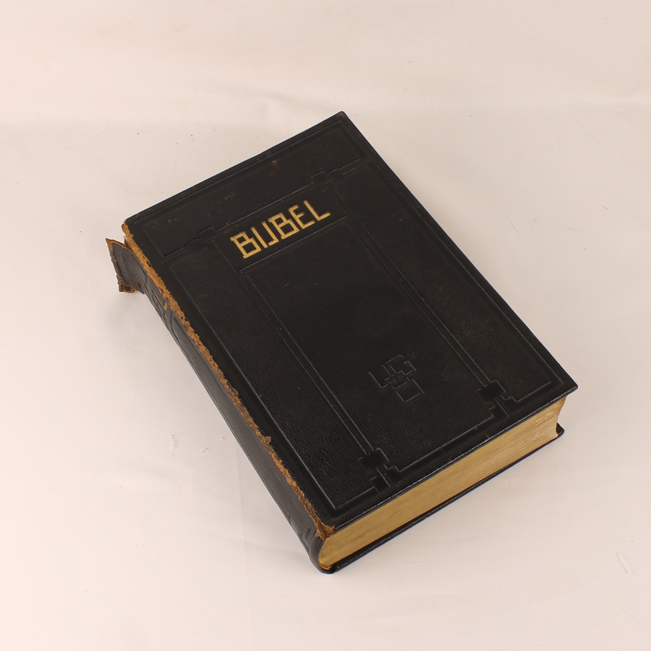 Black leather-bound book titled 'Bible' on a beige background