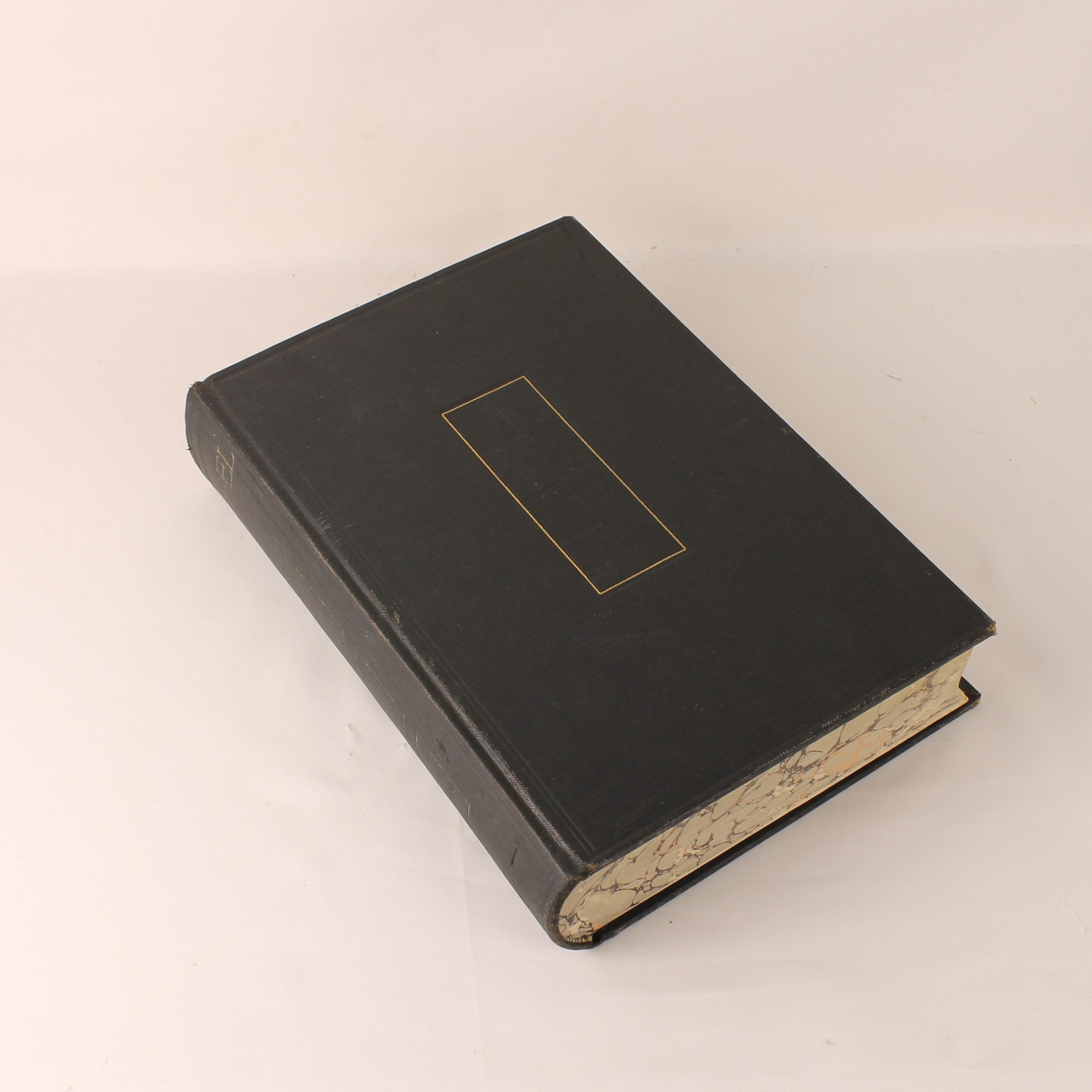 Black leather-bound book with gold stamp on a beige background