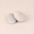 Two gray textured stones on a beige background