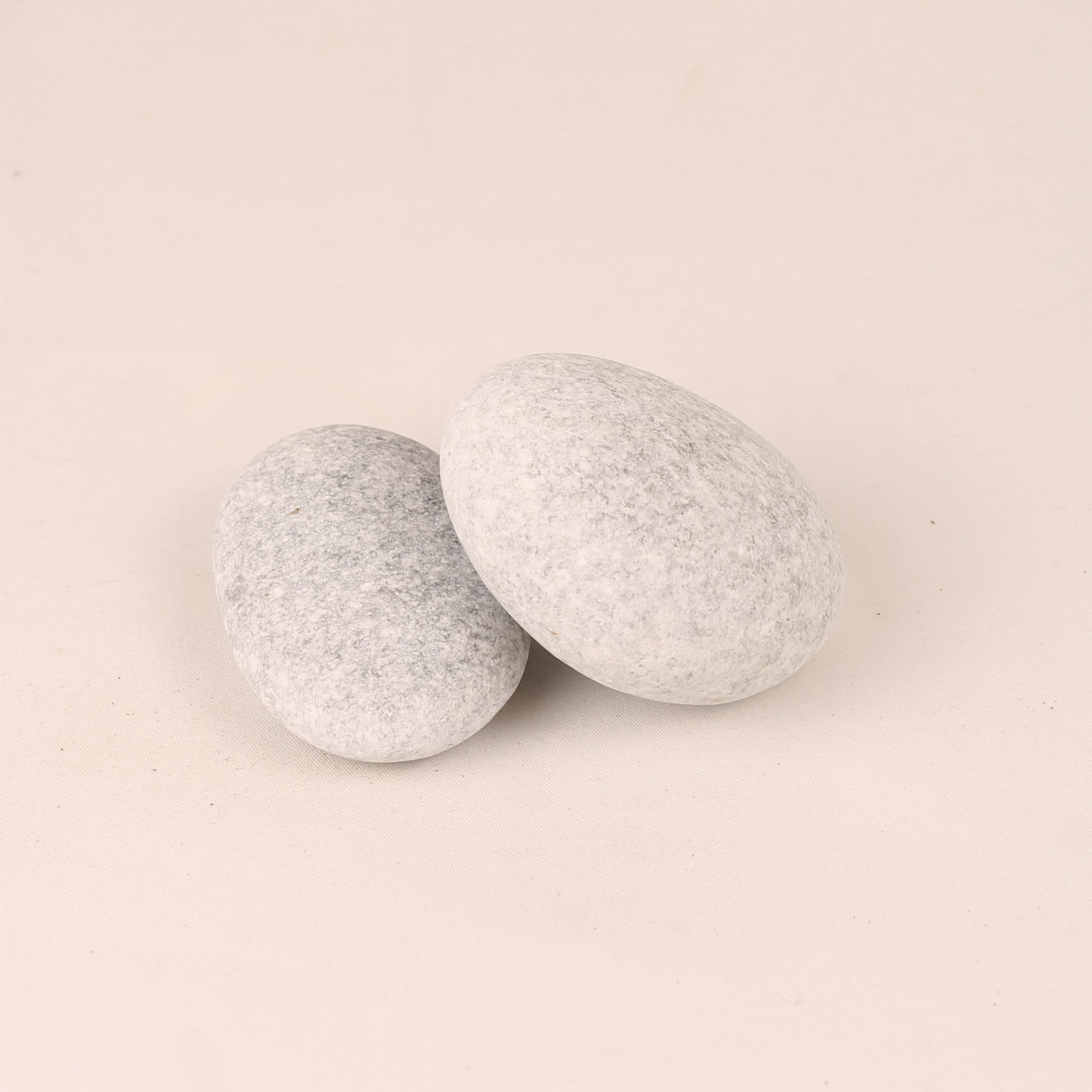 Two gray textured stones on a beige background