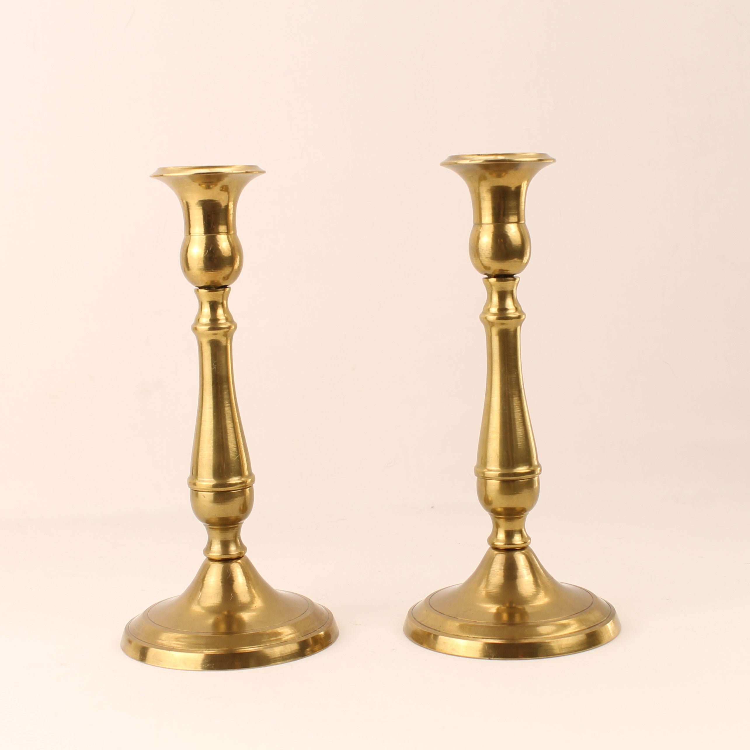 Two gold candle holders on a beige background