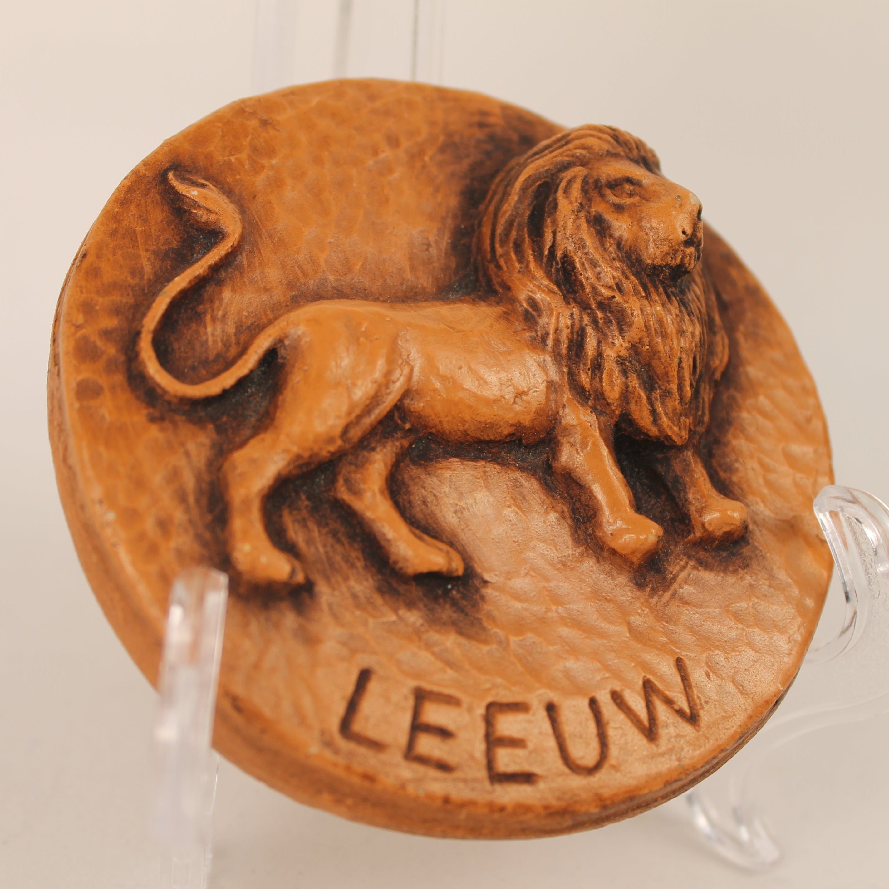 Decorative plaque with a lion design and 'LEEUW' text on a white background