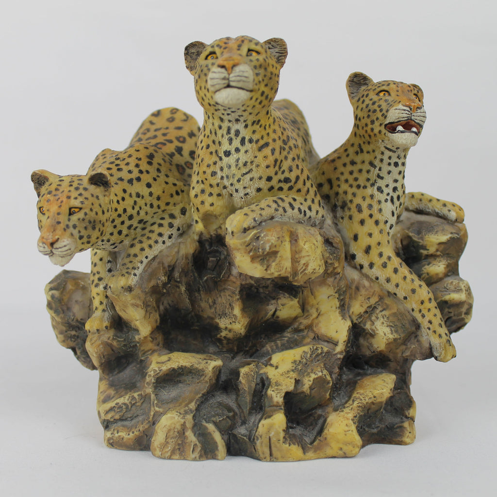 Decorative sculpture of three leopards on a rocky base against a white background