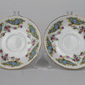 Two decorative ceramic saucers with floral patterns on a gray background