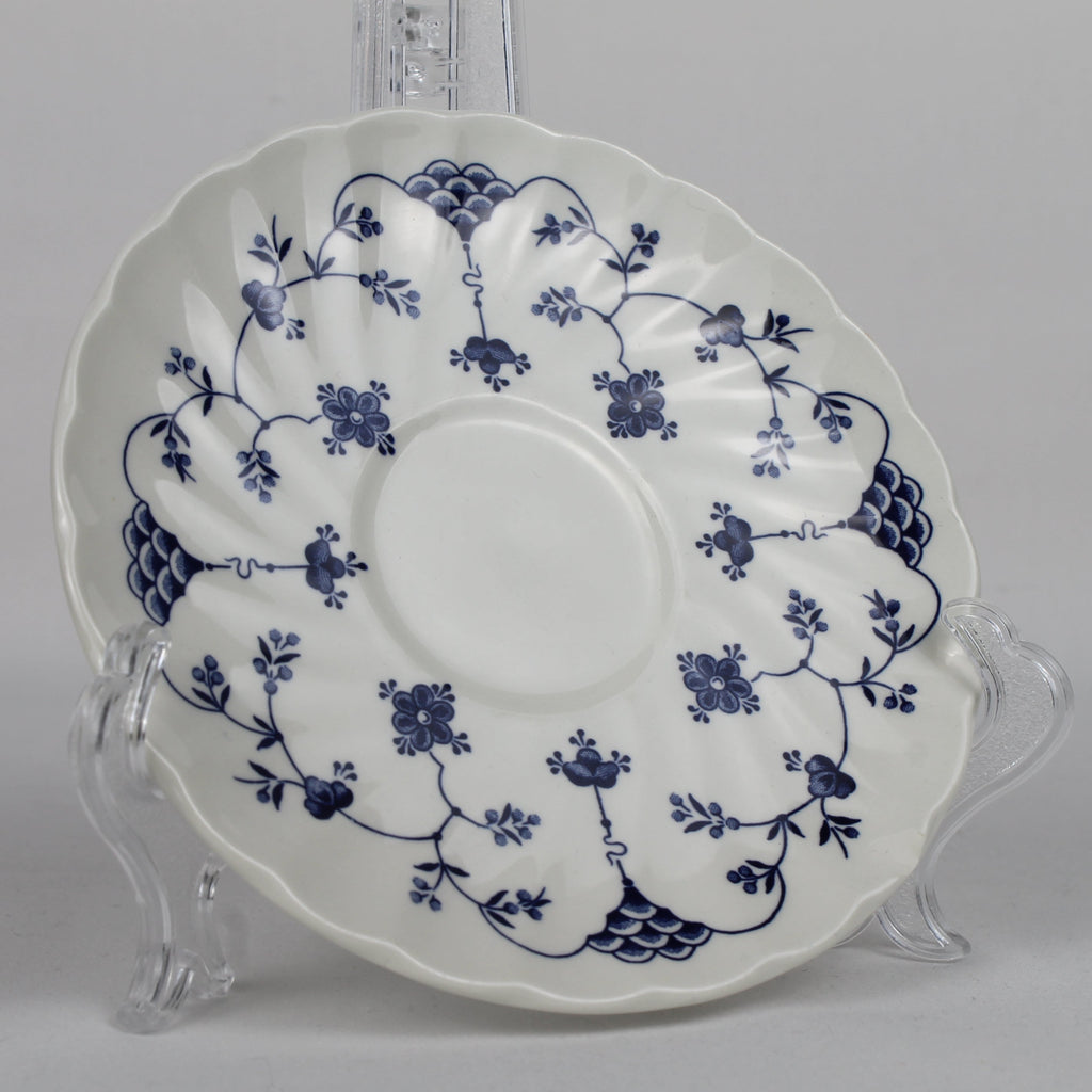 White ceramic plate with blue floral patterns on a clear stand against a gray background