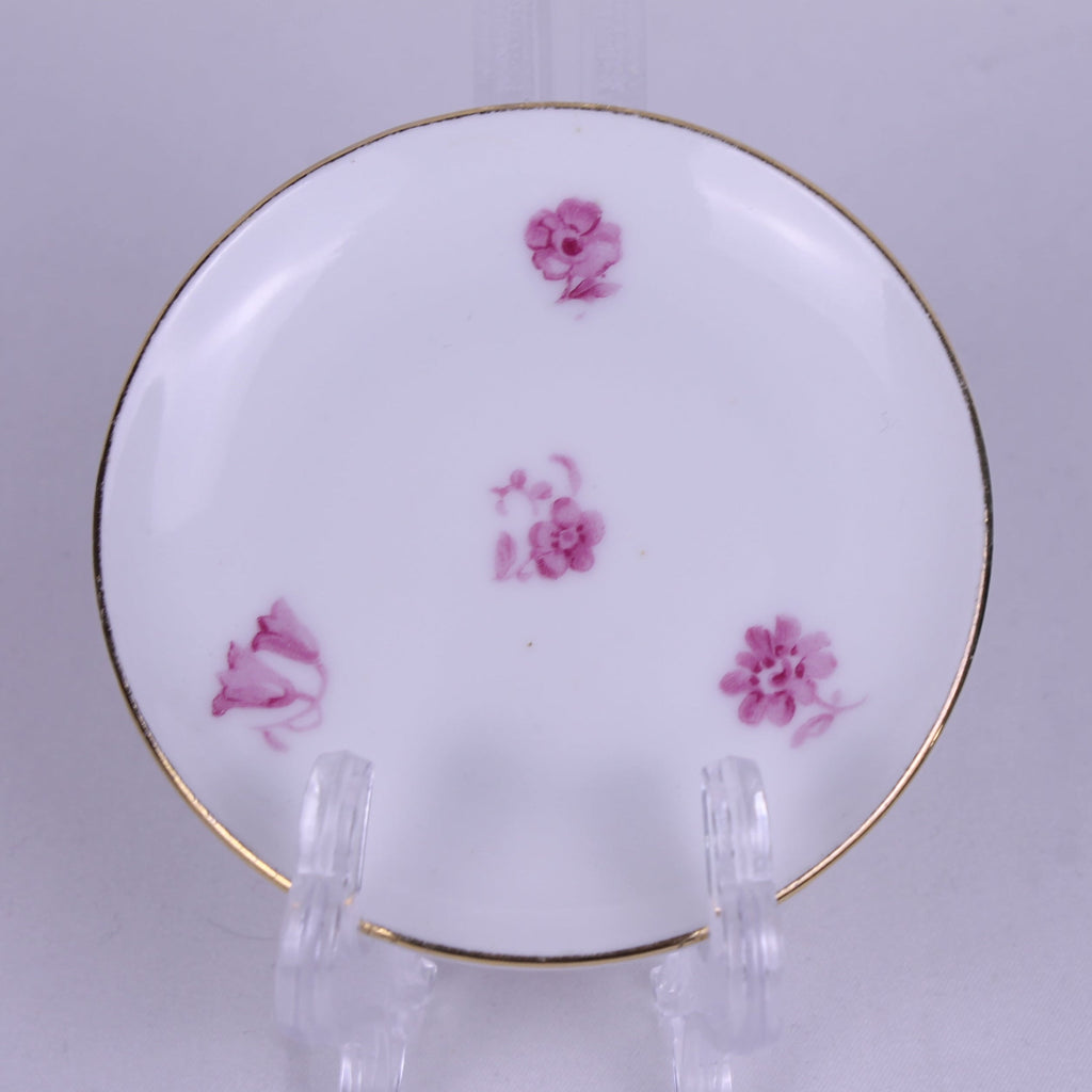 Ceramic plate with pink floral designs on a stand against a light background