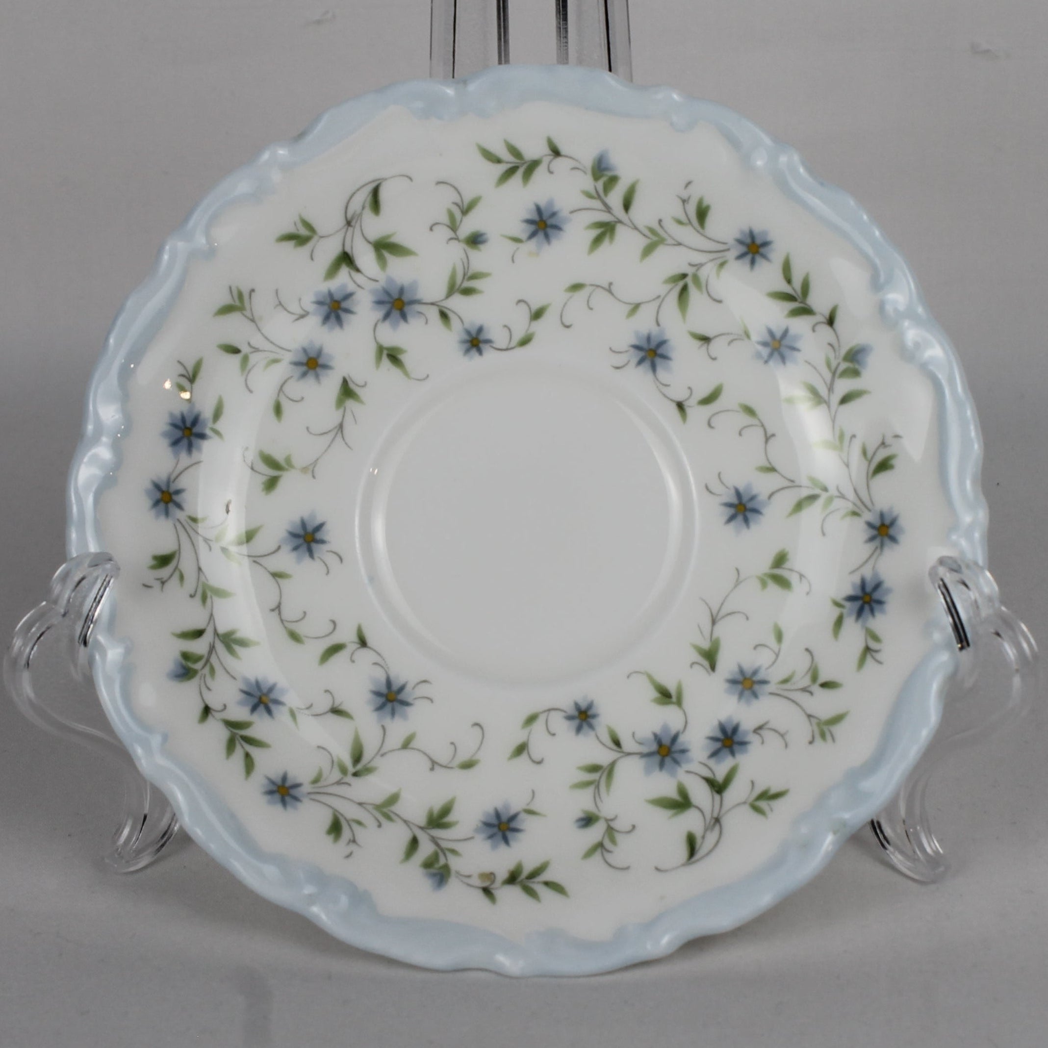 Decorative ceramic plate with floral pattern on a stand against a gray background