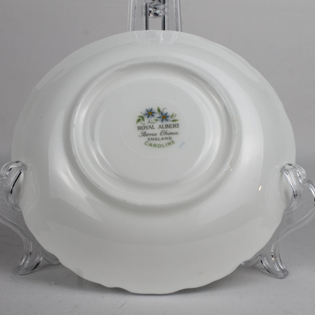 White ceramic plate with 'Royal Albert' branding on a clear stand against a gray background
