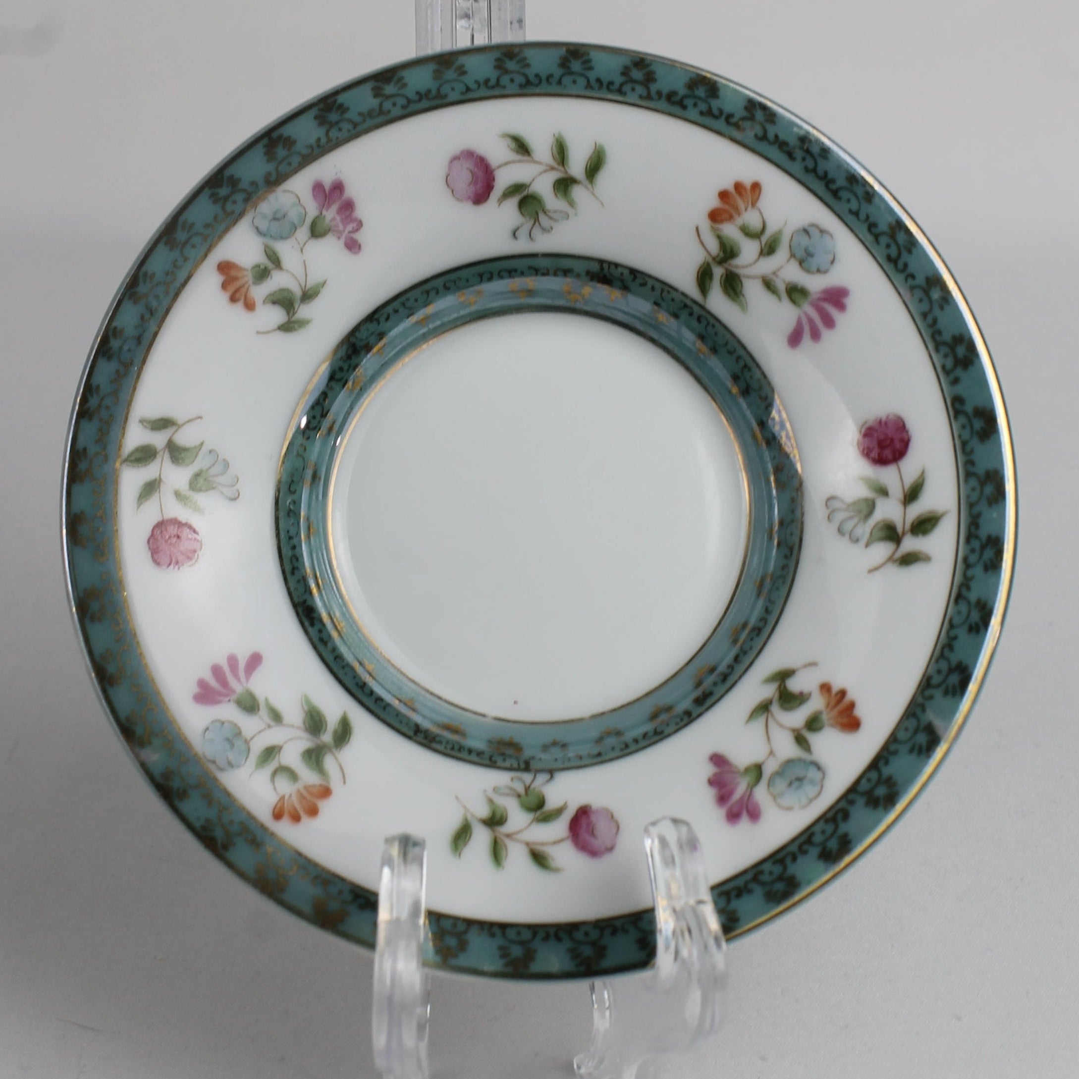Decorative plate with floral patterns on a stand against a white background