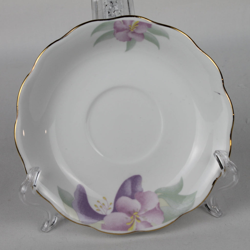 White ceramic saucer with purple floral design on a clear stand against a gray background
