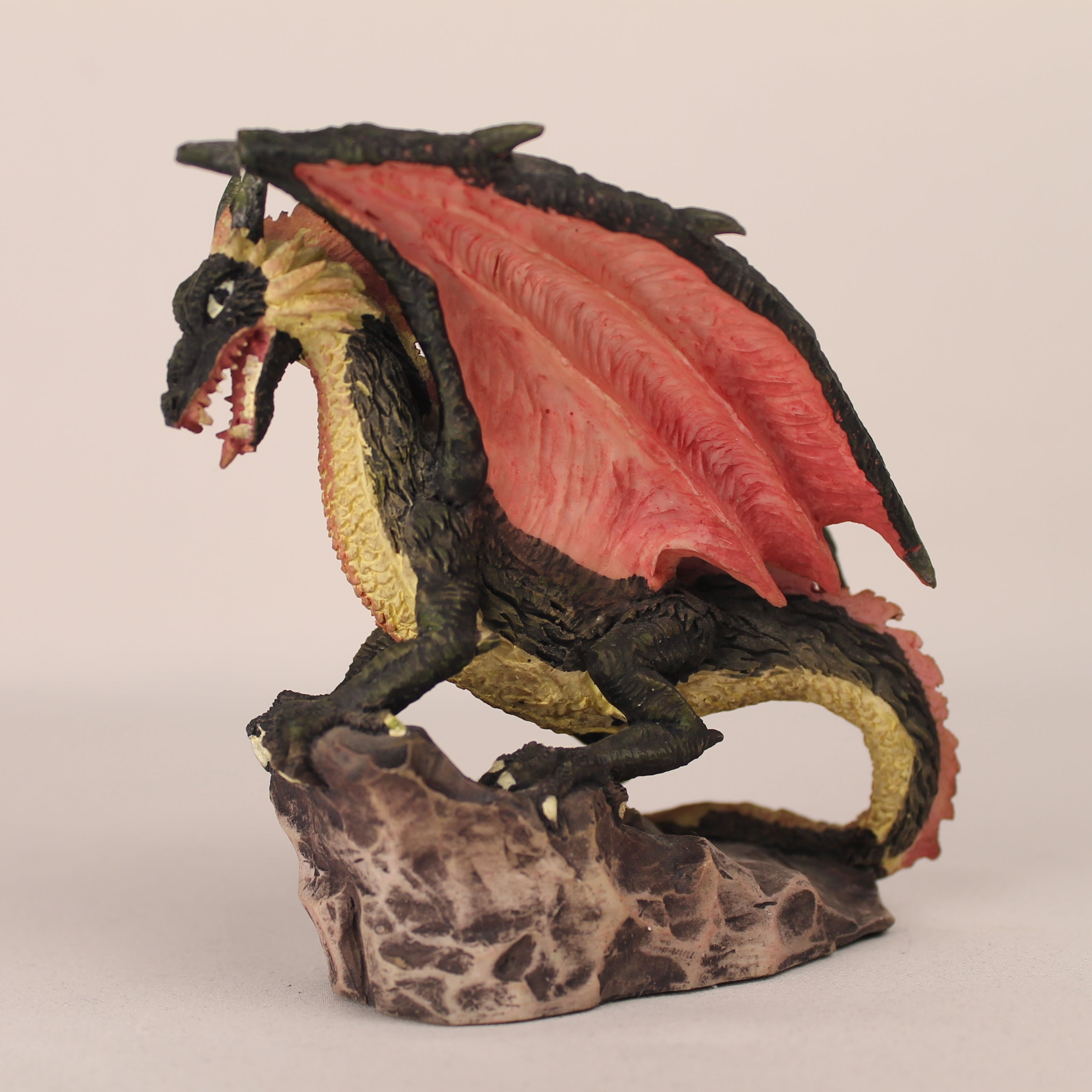 Dragon figurine with red wings on a beige background