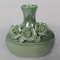 Green ceramic vase with floral designs on a white background