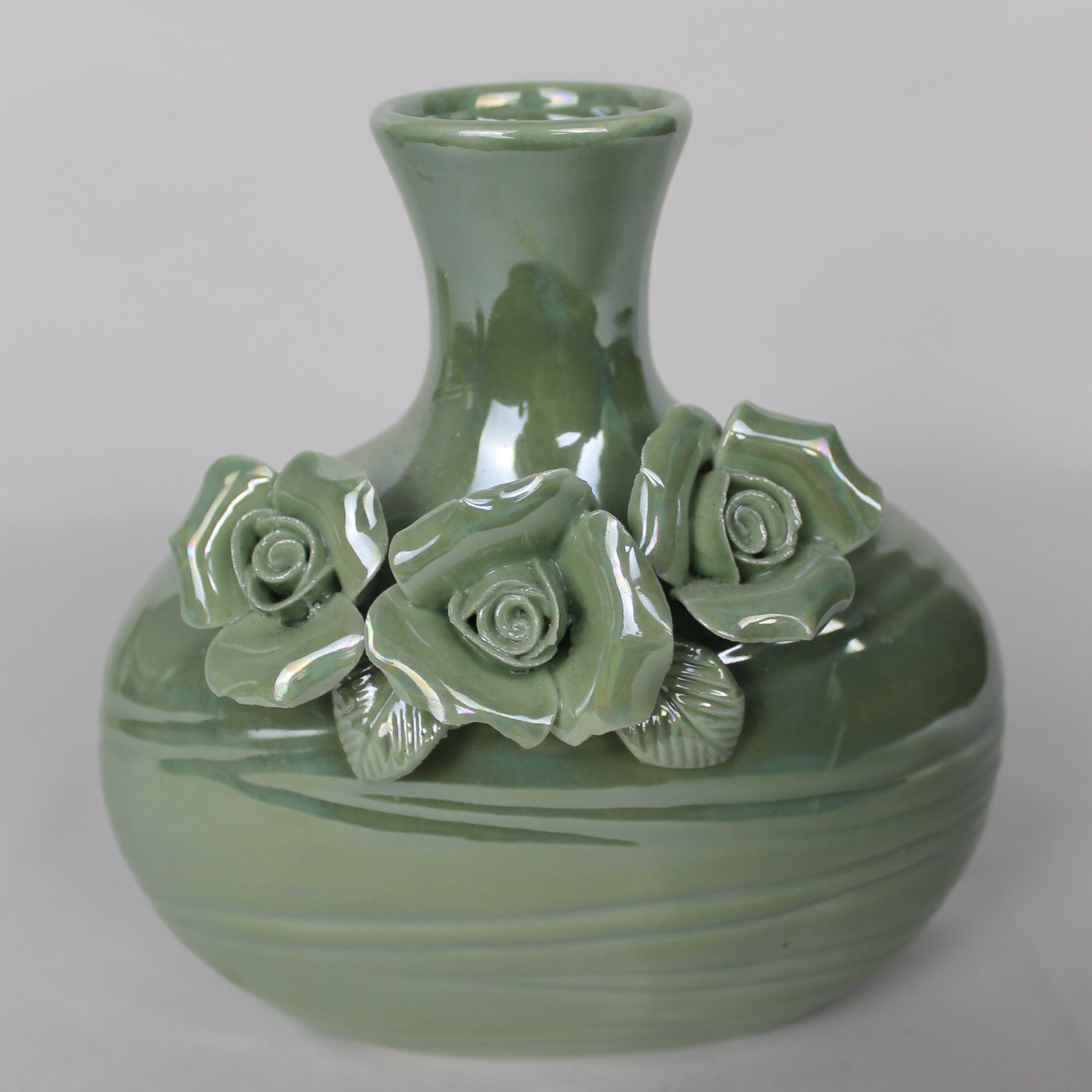 Green ceramic vase with floral designs on a white background