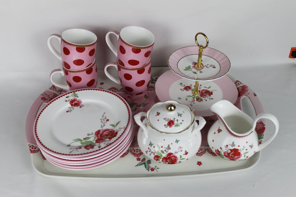 Ceramic tea set with pink polka dot cups, floral plates, and matching teacup and saucer on a white background.