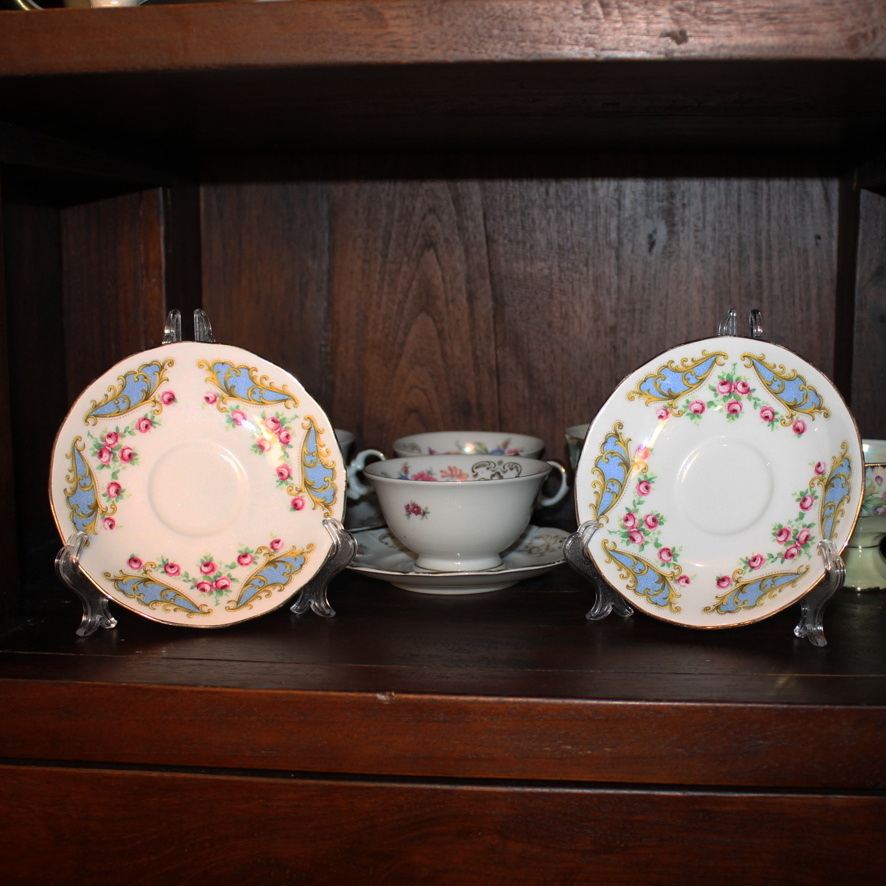 Teacup and saucers with floral patterns on a wooden shelf