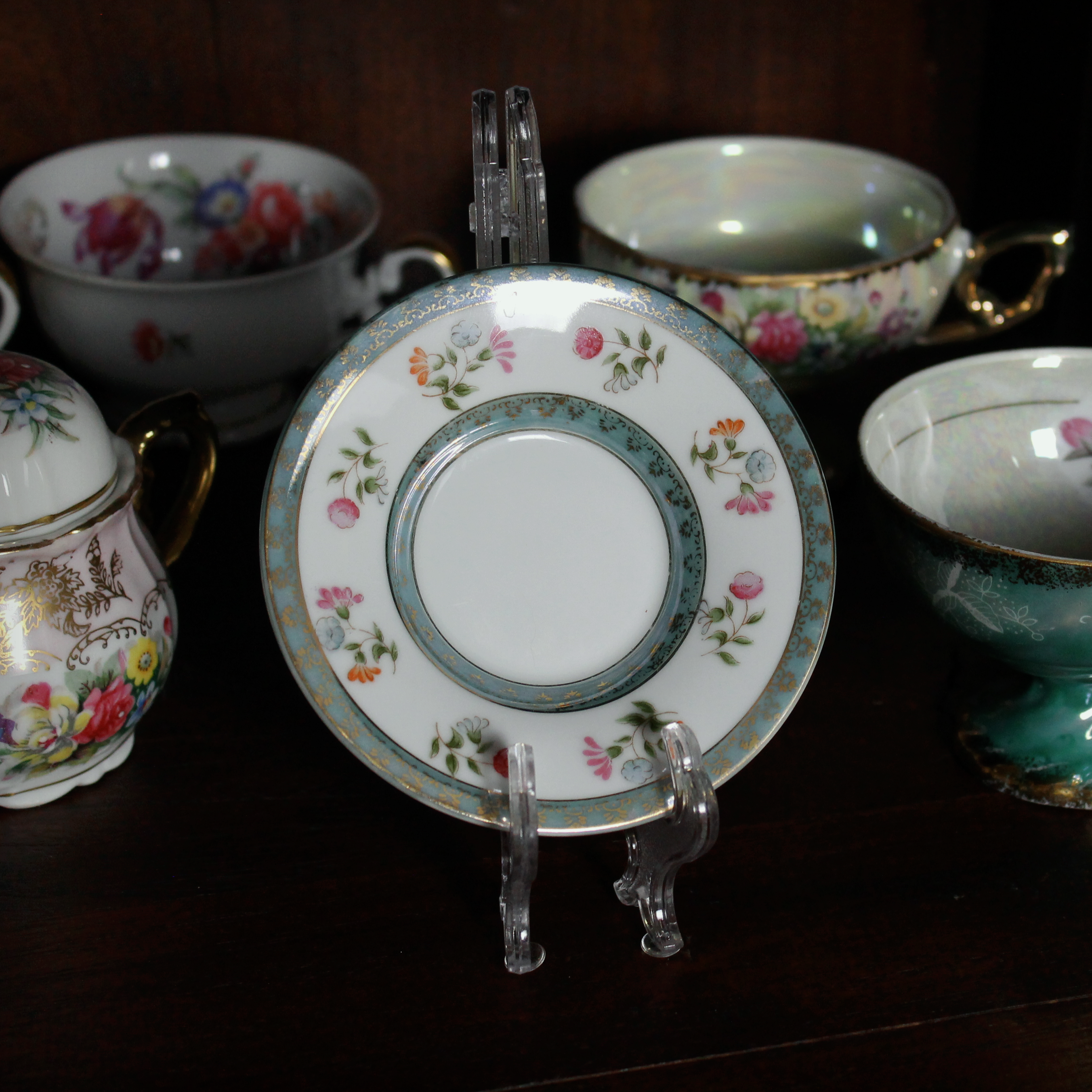 Collection of decorative teacups and saucers on a dark surface